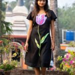 Front view of a woman walking in a handpainted 3D tulip black Malai Cotton dress