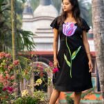 Full-length view of a woman in a black handpainted 3D tulip floral dress