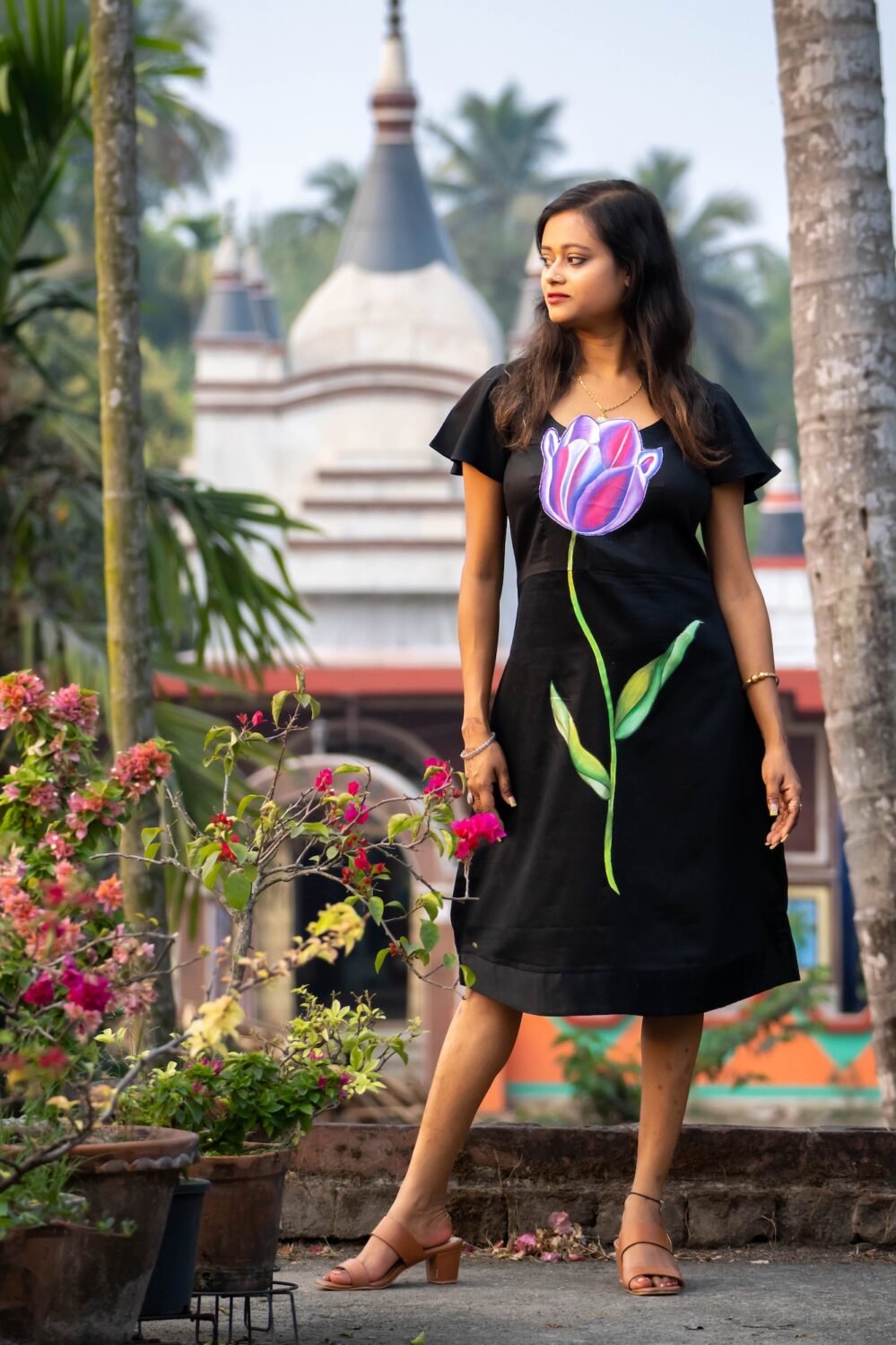 Full-length view of a woman in a black handpainted 3D tulip floral dress
