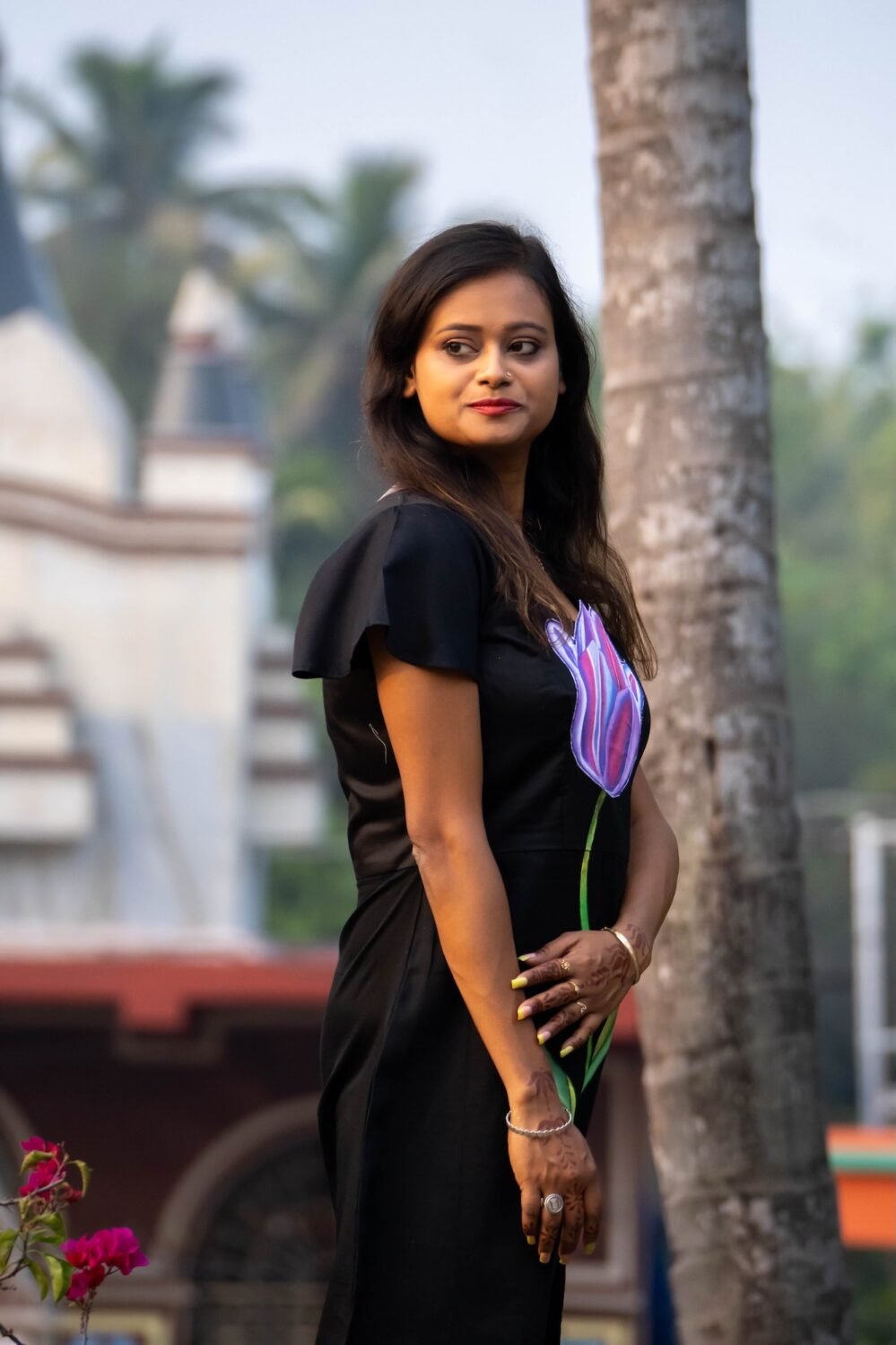 Side profile pose showing sleeve and handpainted tulip design on black dress