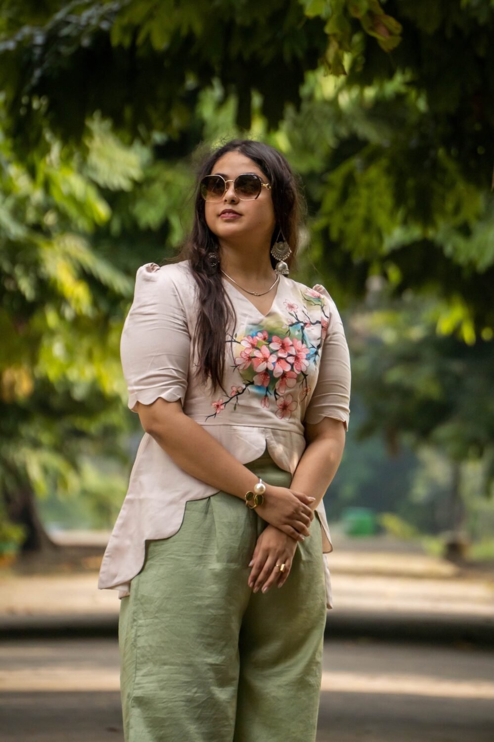 Front-facing medium shot highlighting the V-neckline and intricate cherry blossom painting on a beige asymmetrical scallop top.