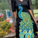 Three-quarter shot of a woman posing outdoors in a black hand-painted peacock Malai Cotton dress