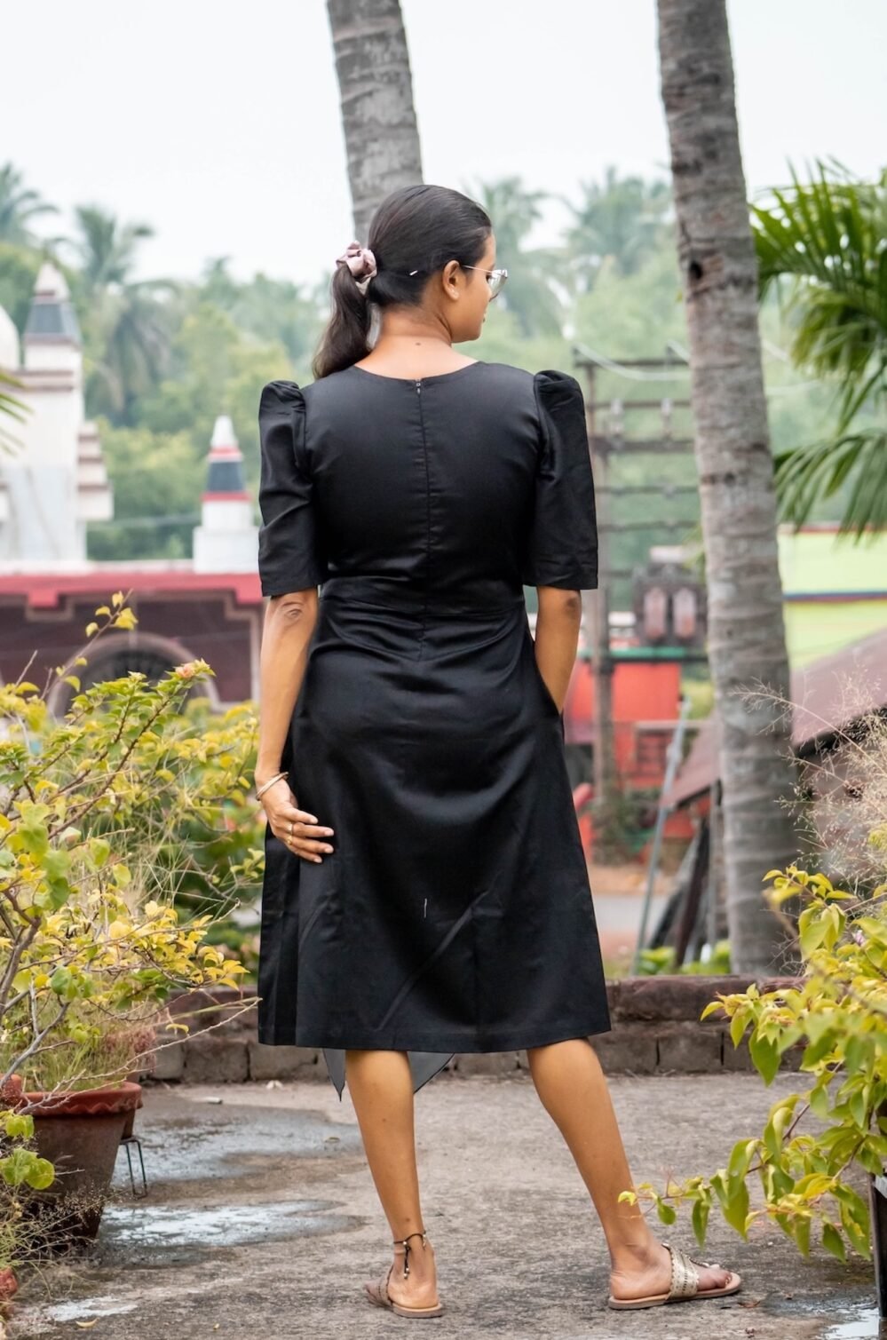 Back view of a black knee-length Malai Cotton midi dress showing puff sleeves and back zip detail