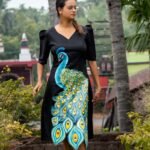 Full-length shot of a woman walking outdoors in a hand painted 3D peacock black midi dress