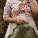 Close-up of the front bodice showing detailed hand-painted pink cherry blossom flowers on a beige scallop top with pearl bracelet accessory