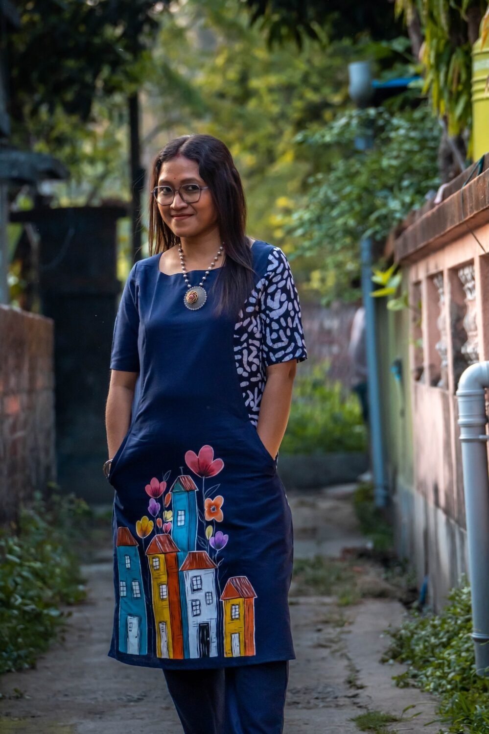 Navy blue straight cotton tunic with functional side pockets and hand-painted houses illustration.