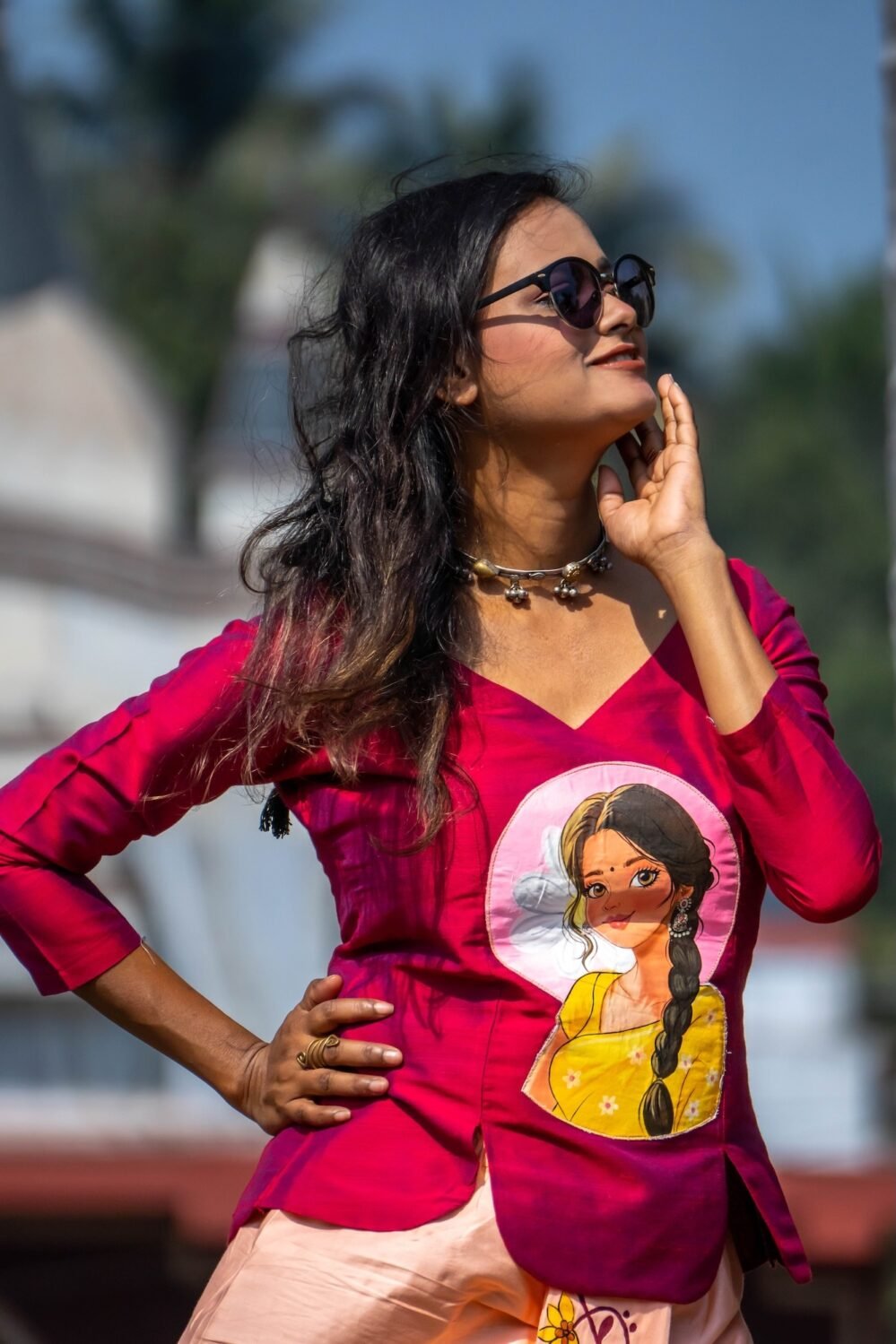 Model wearing sunglasses posing in the Nayantara magenta hand-painted portrait top and peach dhoti pant set