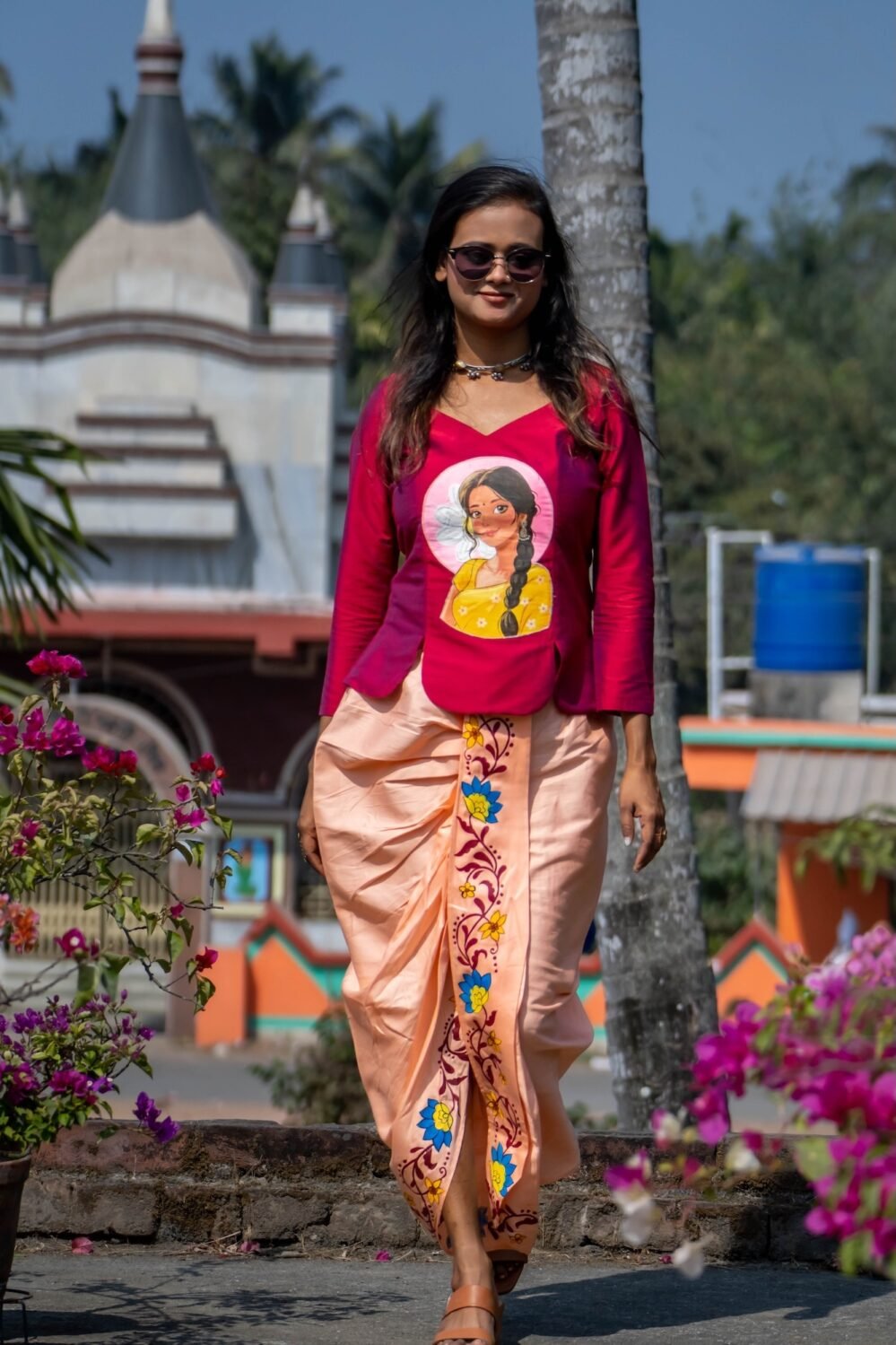 Full-length view of a model walking outdoors in the Nayantara hand-painted portrait top and floral dhoti pants