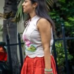 Side profile view of model wearing a sleeveless hand-painted lotus top with keyhole tie-up neckline and red skirt