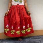 Front view showing the full flare and hand-painted lotus design on the red Malai Cotton skirt