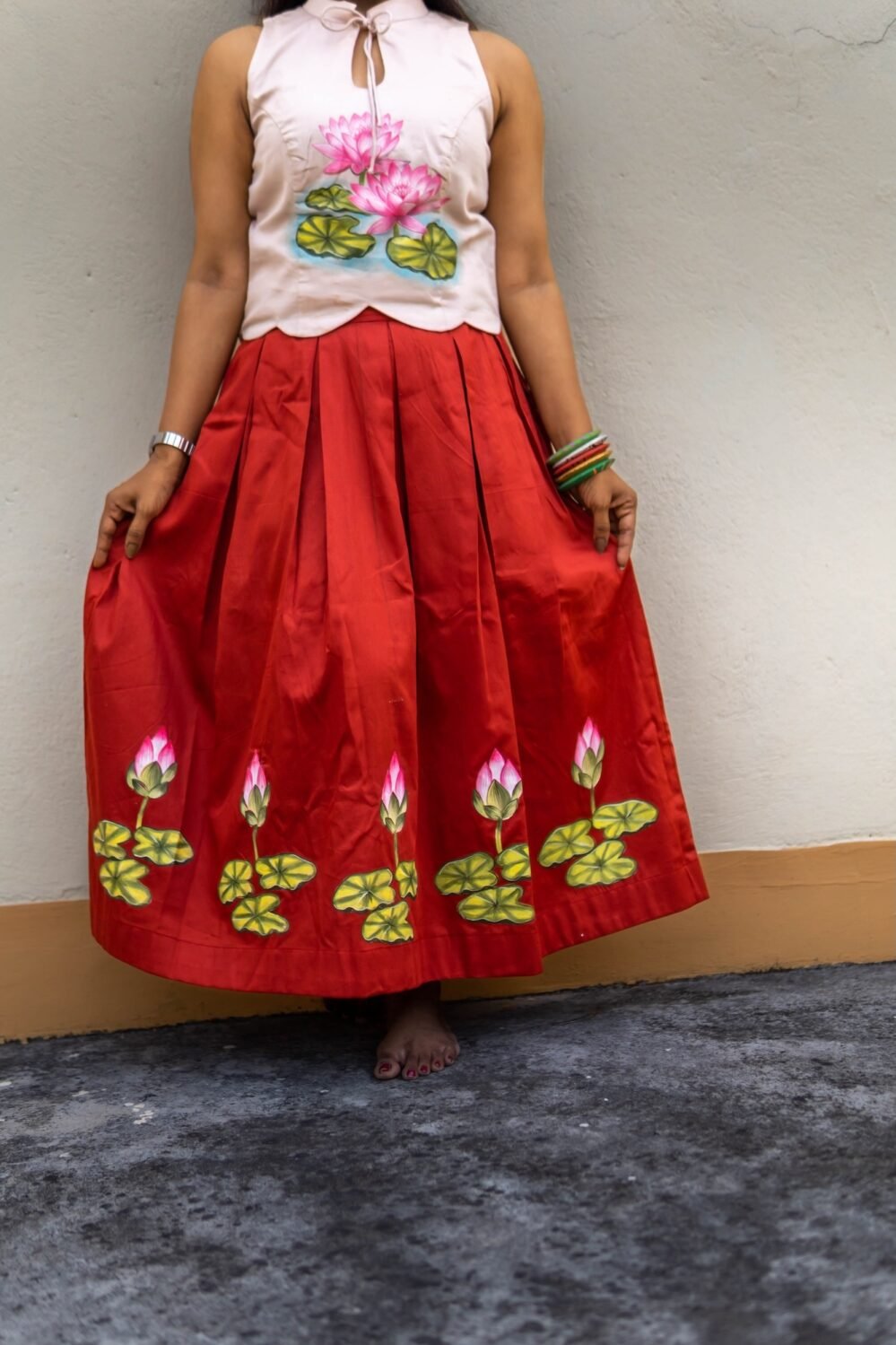 Front view showing the full flare and hand-painted lotus design on the red Malai Cotton skirt