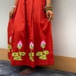 Lower shot showing the hand-painted lotus flower motifs along the pleated red skirt hem