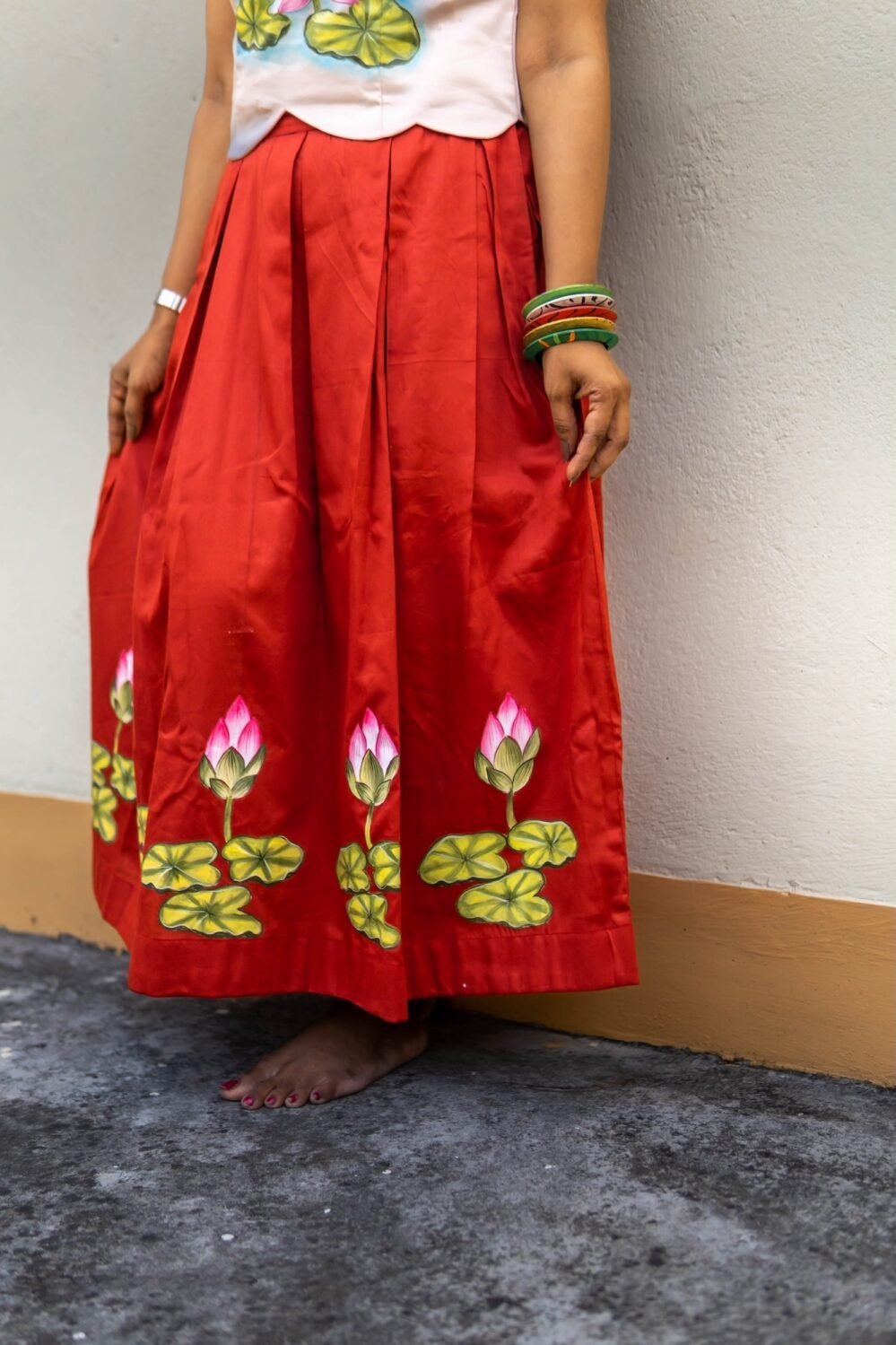 Lower shot showing the hand-painted lotus flower motifs along the pleated red skirt hem