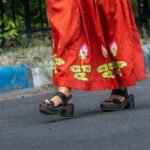 Close-up shot of hand-painted lotus flower motifs painted along the bottom hem of a red Malai Cotton skirt