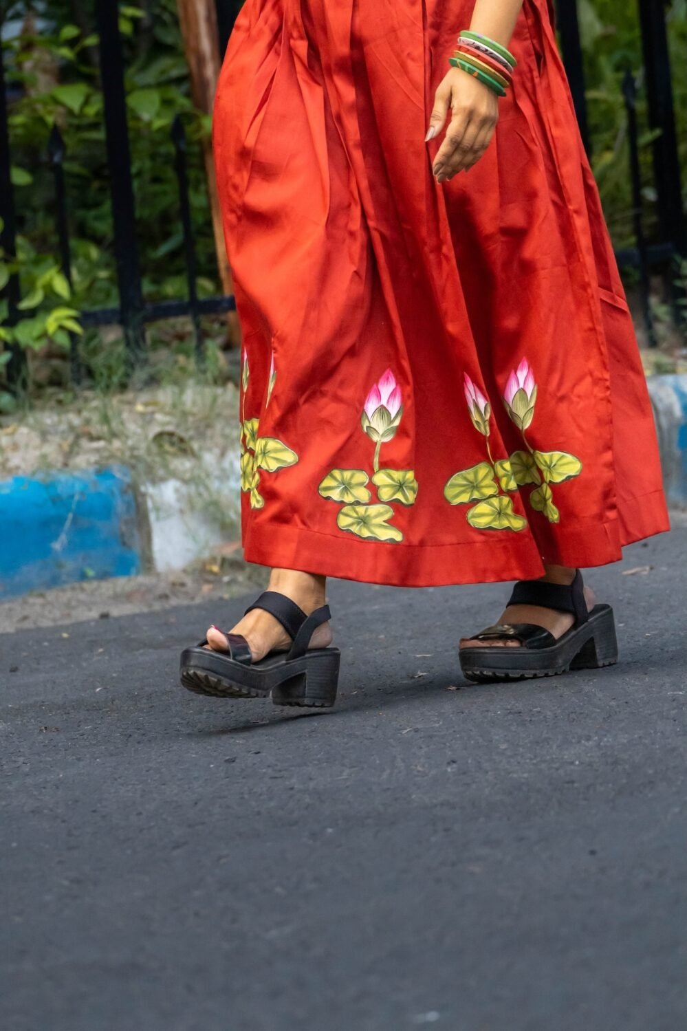 Close-up shot of hand-painted lotus flower motifs painted along the bottom hem of a red Malai Cotton skirt