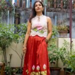 Full-length shot of model wearing hand-painted lotus top and flared red Malai Cotton skirt