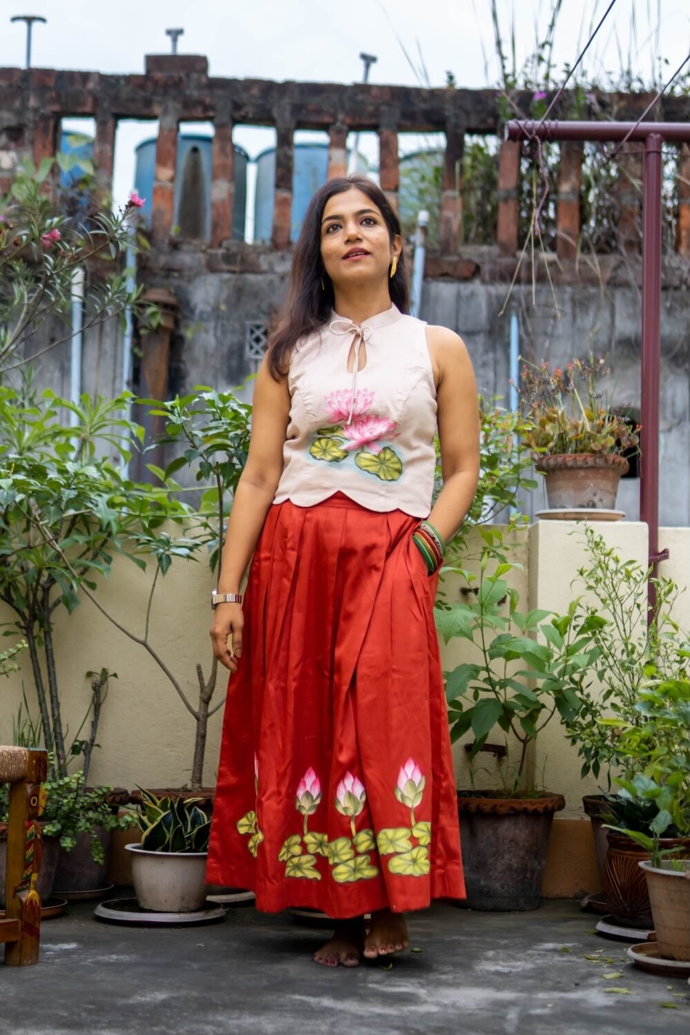 Full-length shot of model wearing hand-painted lotus top and flared red Malai Cotton skirt