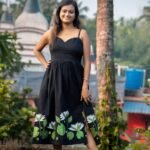 Full view of woman wearing black hand-painted floral midi dress with sweetheart neckline
