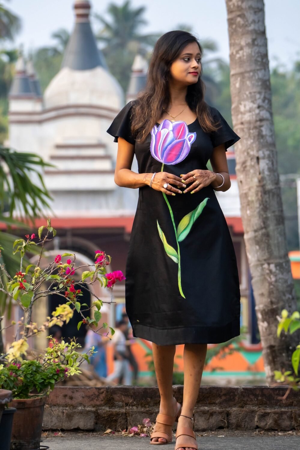 Model posing outdoors wearing a handpainted 3D purple tulip black Malai Cotton midi dress