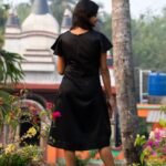Back view of model wearing a black Malai Cotton dress outdoors