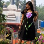 Full shot of model wearing handpainted 3D purple tulip black dress looking down