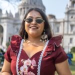 Portrait view of Mridu hand-painted floral maroon cotton dress with lace trim.
