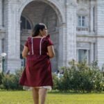 Back angle shot of model walking in Mridu maroon hand-painted cotton dress.