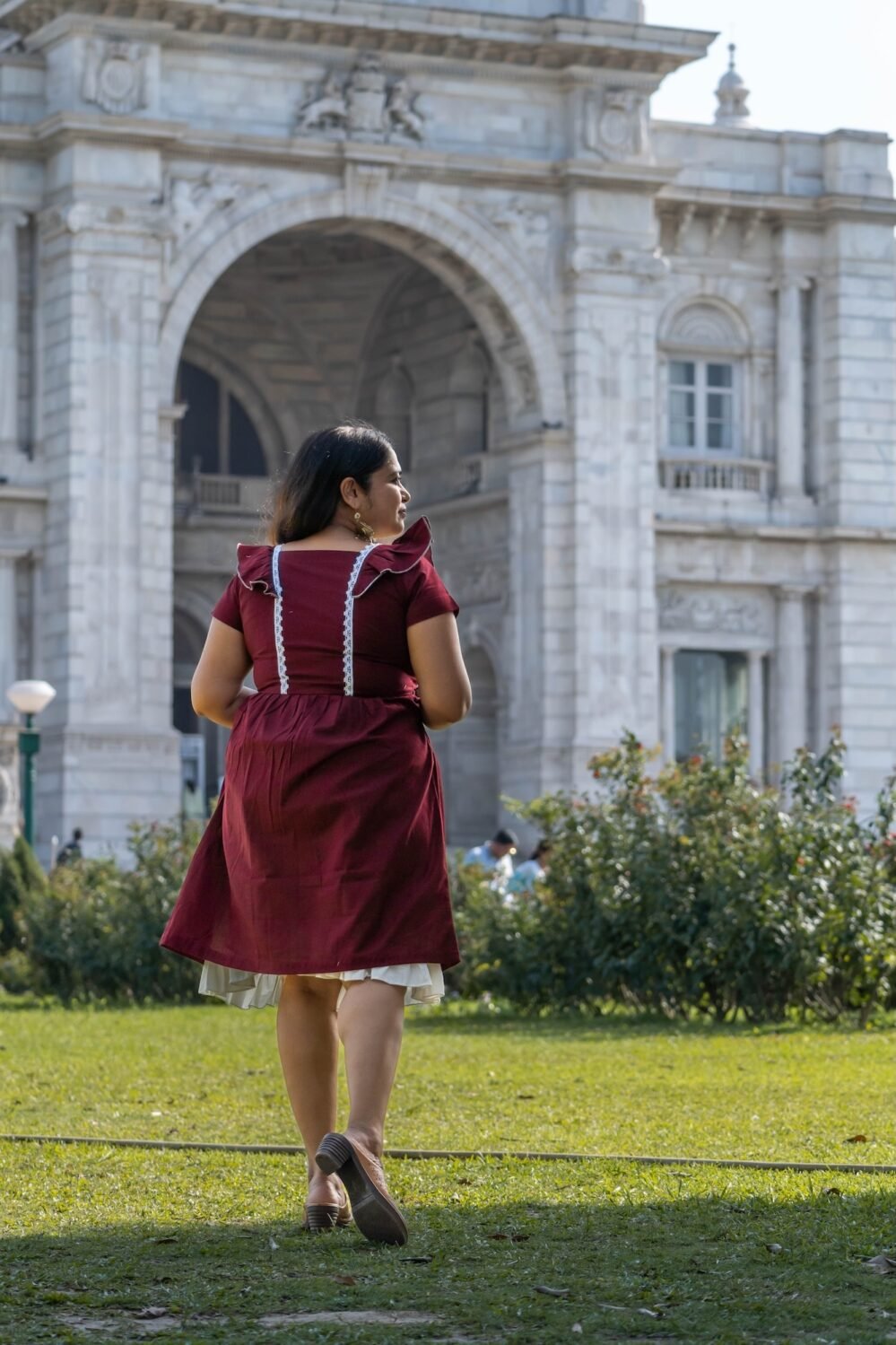 Back angle shot of model walking in Mridu maroon hand-painted cotton dress.