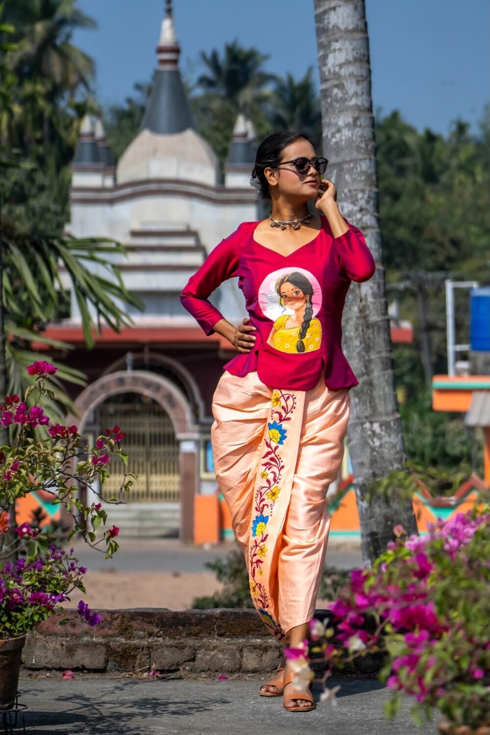 Model standing in a traditional outdoor setting wearing the Nayantara hand-painted fusion dhoti set