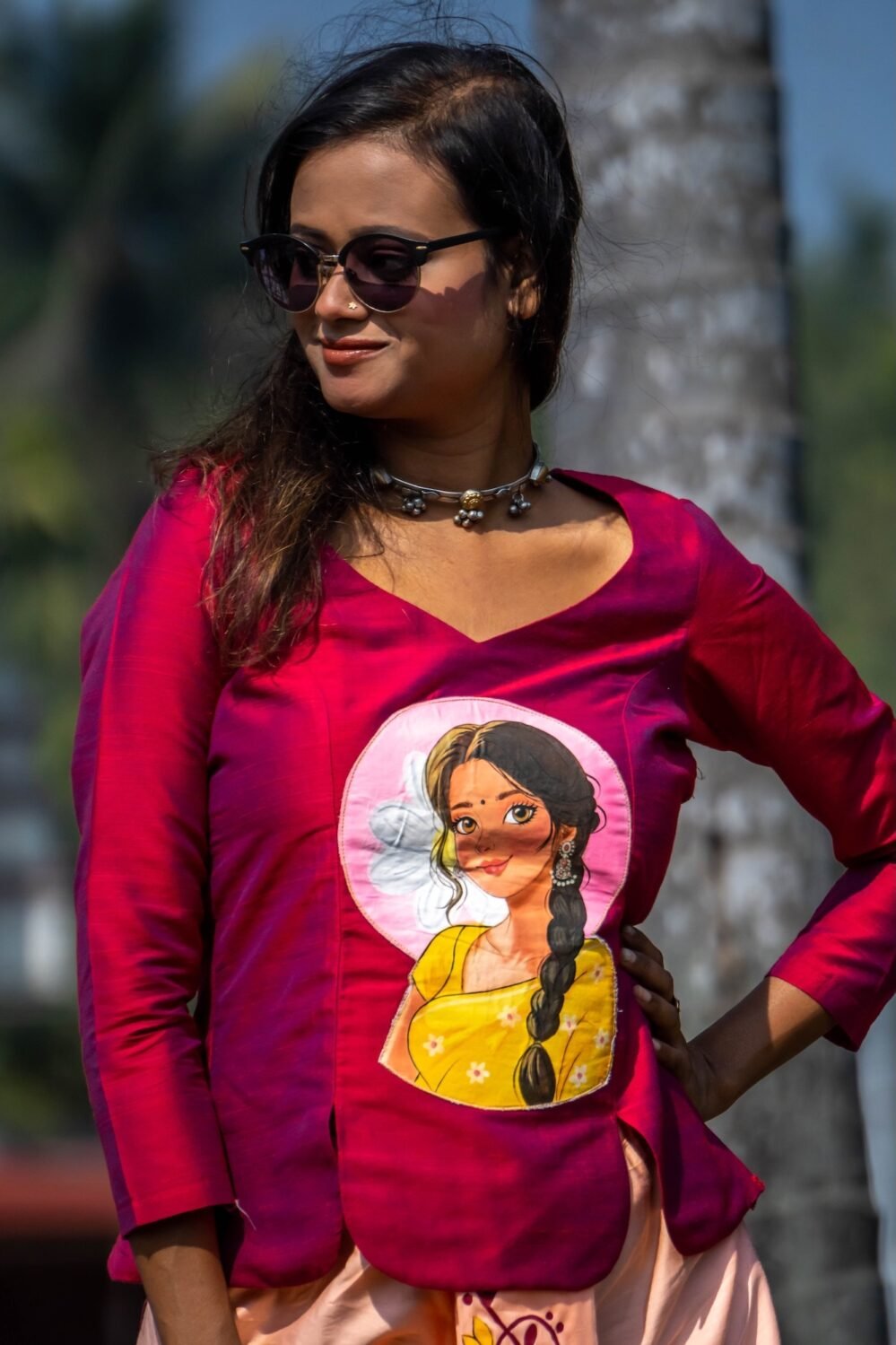 Close-up view of the hand-painted portrait motif on the deep magenta V-neck top from the Nayantara collection