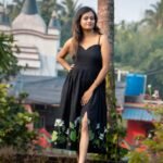 Front profile shot of model posing in black hand-painted water lily dress with front slit