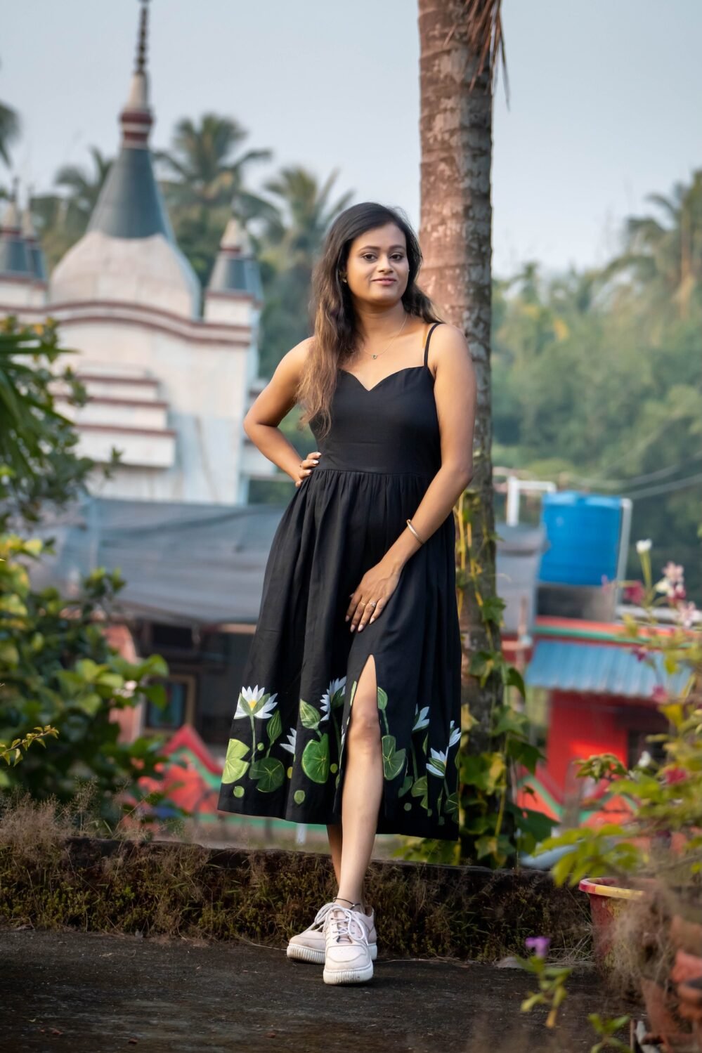 Front profile shot of model posing in black hand-painted water lily dress with front slit