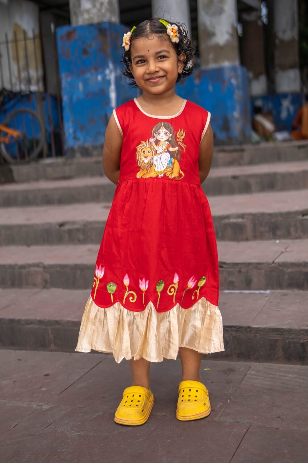 Full front view of girl smiling in red handpainted Durga Rani frock with lotus motifs by Aankibukis Couture.