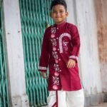 Boy walking gracefully in a maroon hand painted Bengali dhoti set designed for Durga Puja and cultural events.