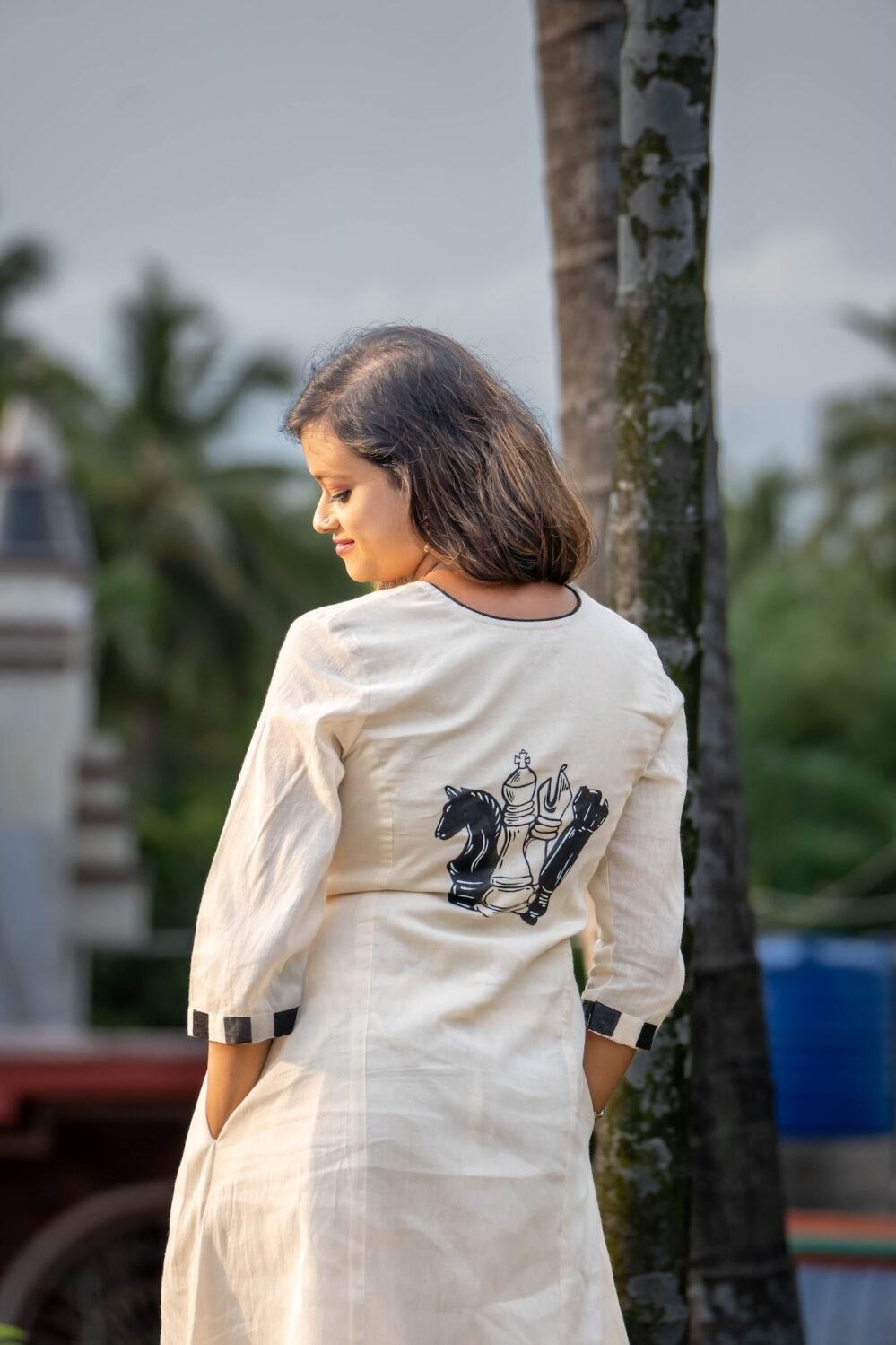 Closeup view in portrait style of white Kora Khadi co-ord set featuring handpainted chess piece artwork on the back
