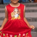Close-up view showing handpainted lotus artwork, scalloped hemline, and golden frill of the Durga Rani kids frock.