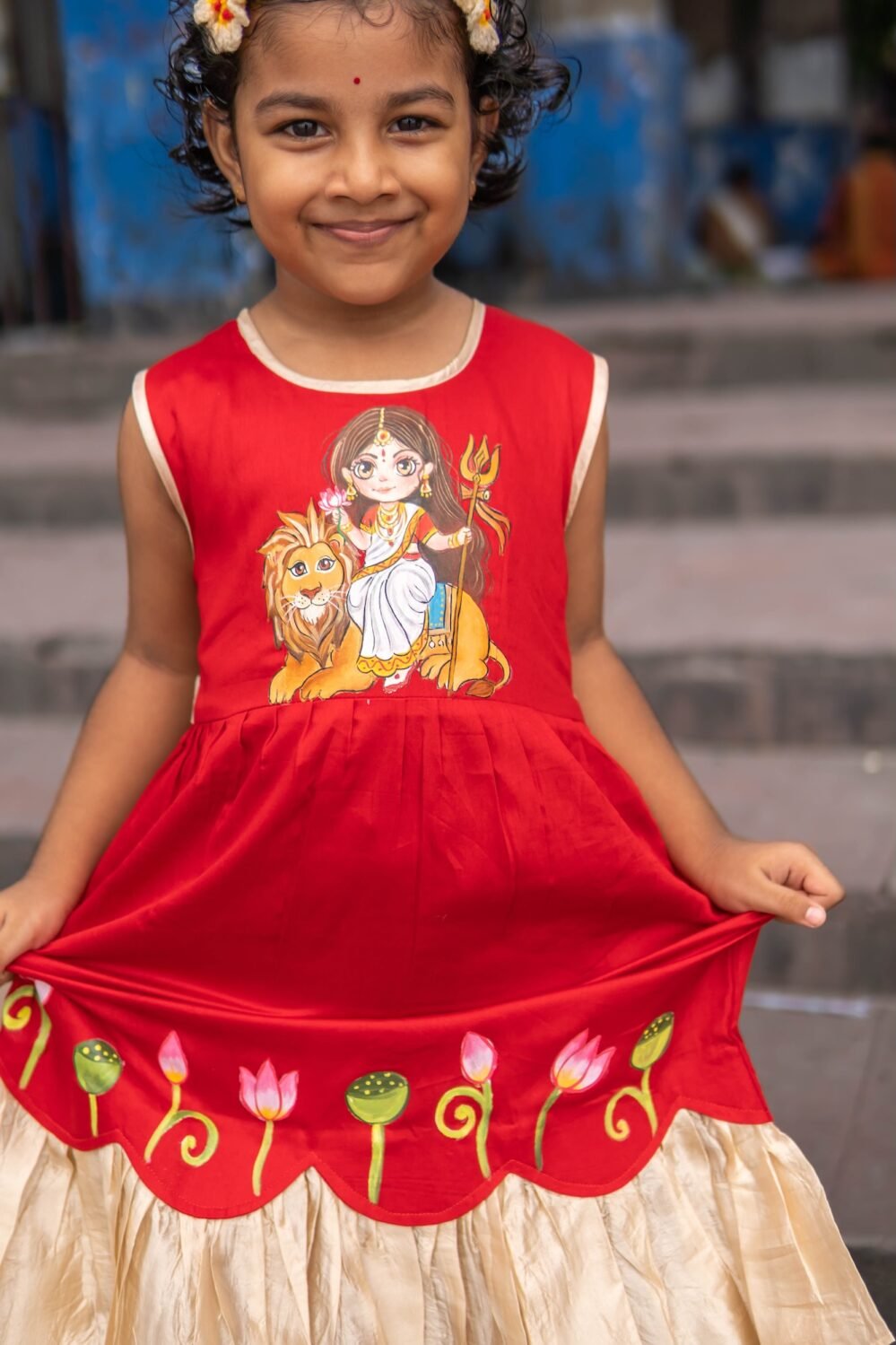 Close-up view showing handpainted lotus artwork, scalloped hemline, and golden frill of the Durga Rani kids frock.