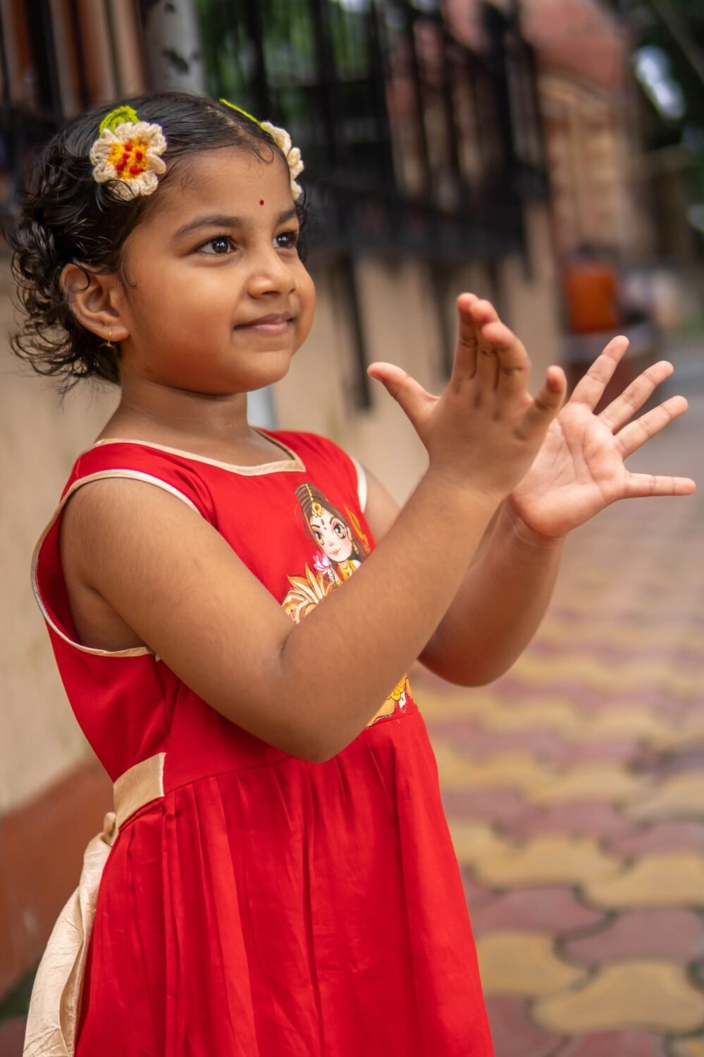 Side angle close-up showing golden adjustable waist tie-up belt on red handpainted kids frock.