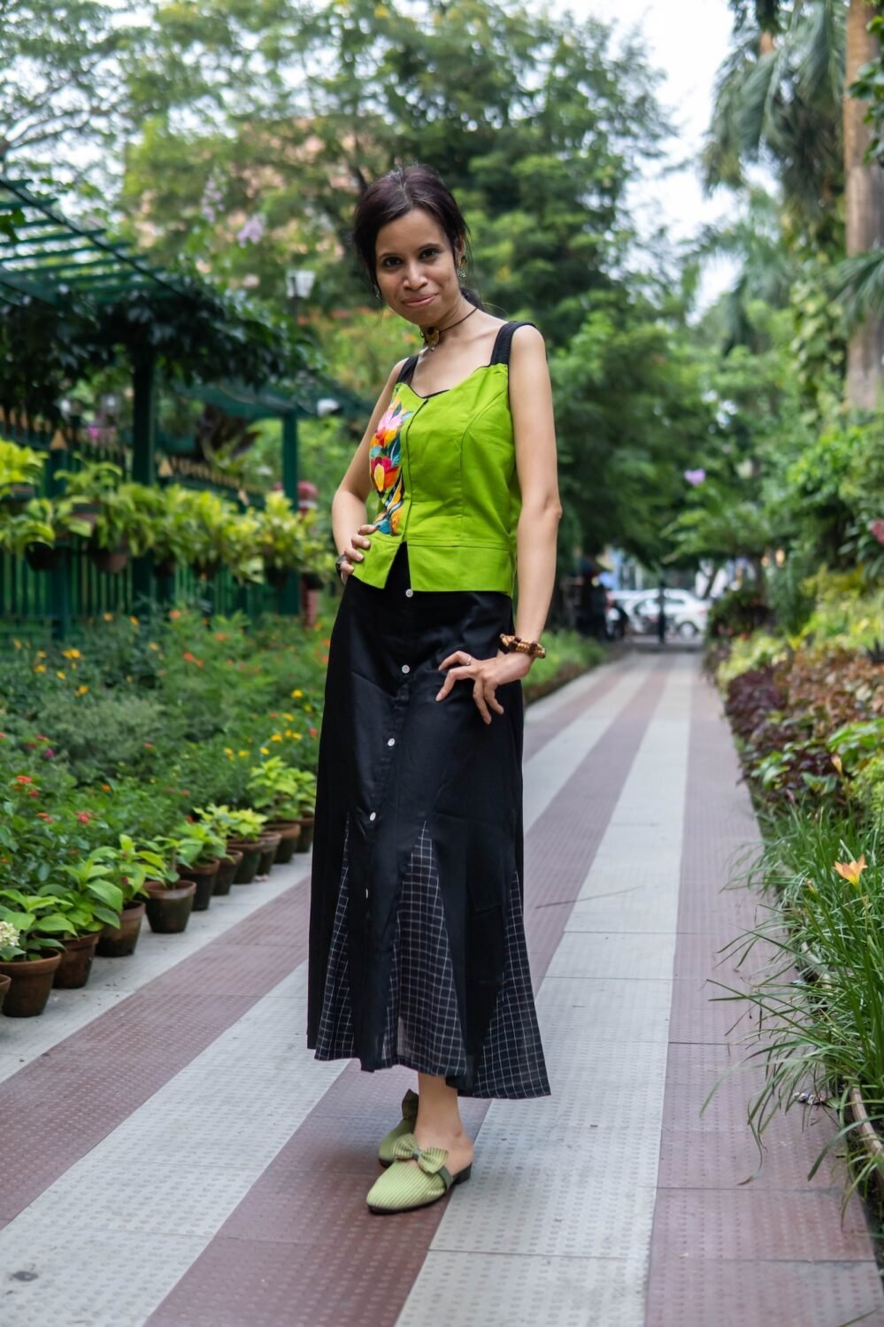 Full-length view of the Flora Canvas skirt co-ord featuring a hand-painted neon green top on a garden walkway