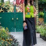 model wearing Aankibukis Couture Flora Canvas hand-painted neon green top and long black skirt set standing outdoors