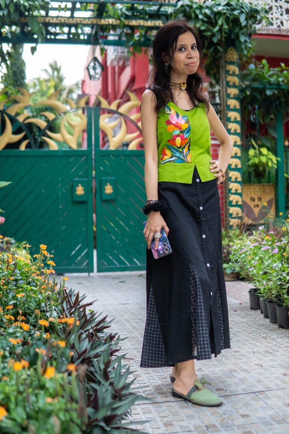 model wearing Aankibukis Couture Flora Canvas hand-painted neon green top and long black skirt set standing outdoors