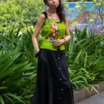 Model wearing Aankibukis Couture Flora Canvas hand-painted neon green sleeveless top and long black skirt set standing outdoors