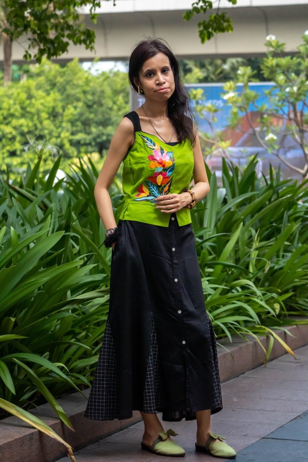Model wearing Aankibukis Couture Flora Canvas hand-painted neon green sleeveless top and long black skirt set standing outdoors