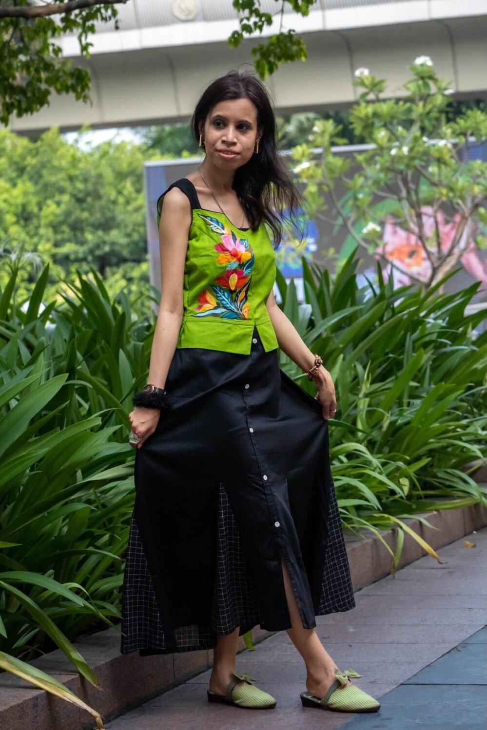 Model lifting the sides of the Flora Canvas black skirt showcasing the check koli lower hem panels