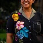 Macro view of hand-painted botanical motifs and contrast button-down placket on a black handloom cotton blazer-collar shirt.