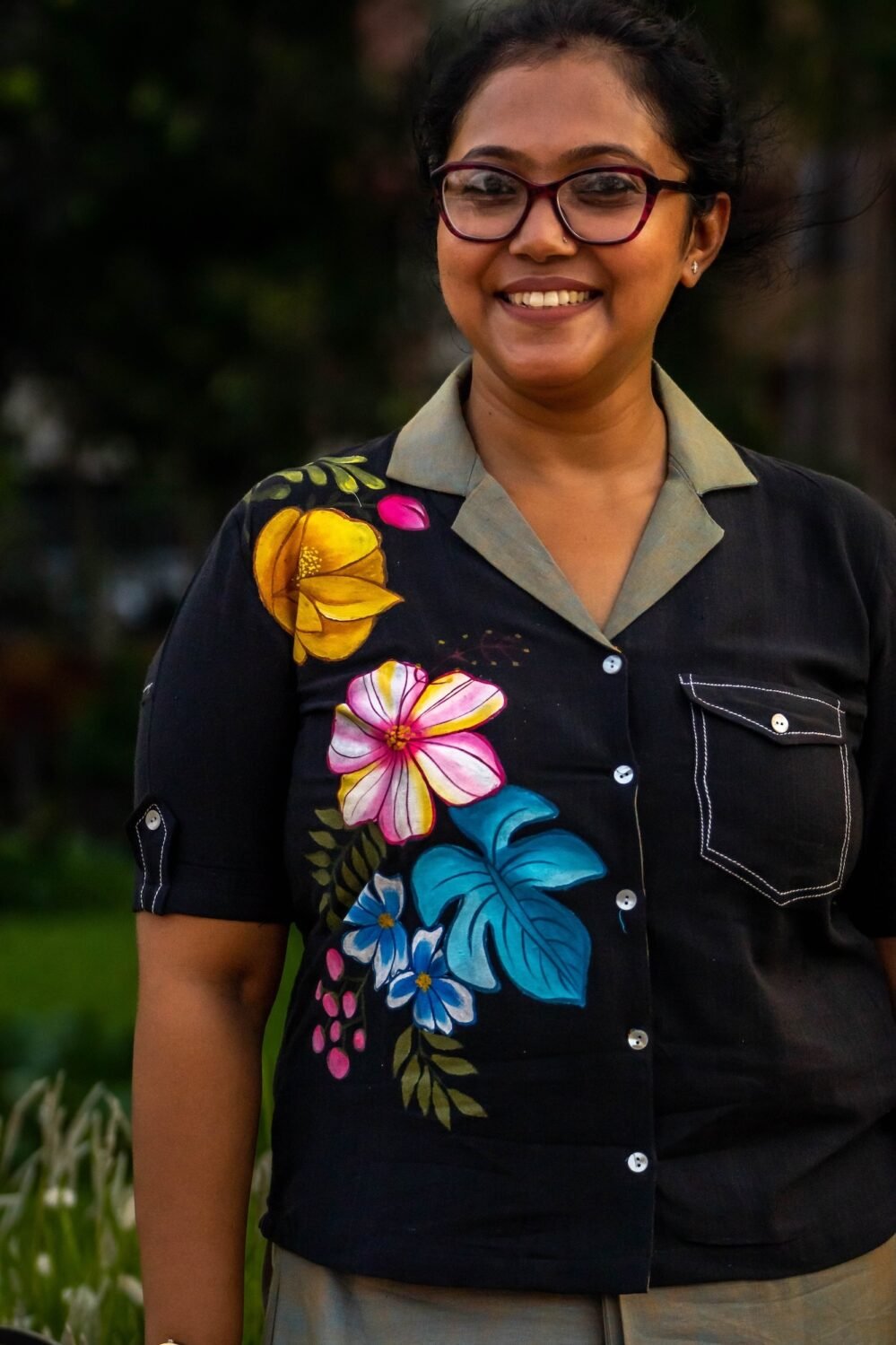 Macro view of hand-painted botanical motifs and contrast button-down placket on a black handloom cotton blazer-collar shirt.