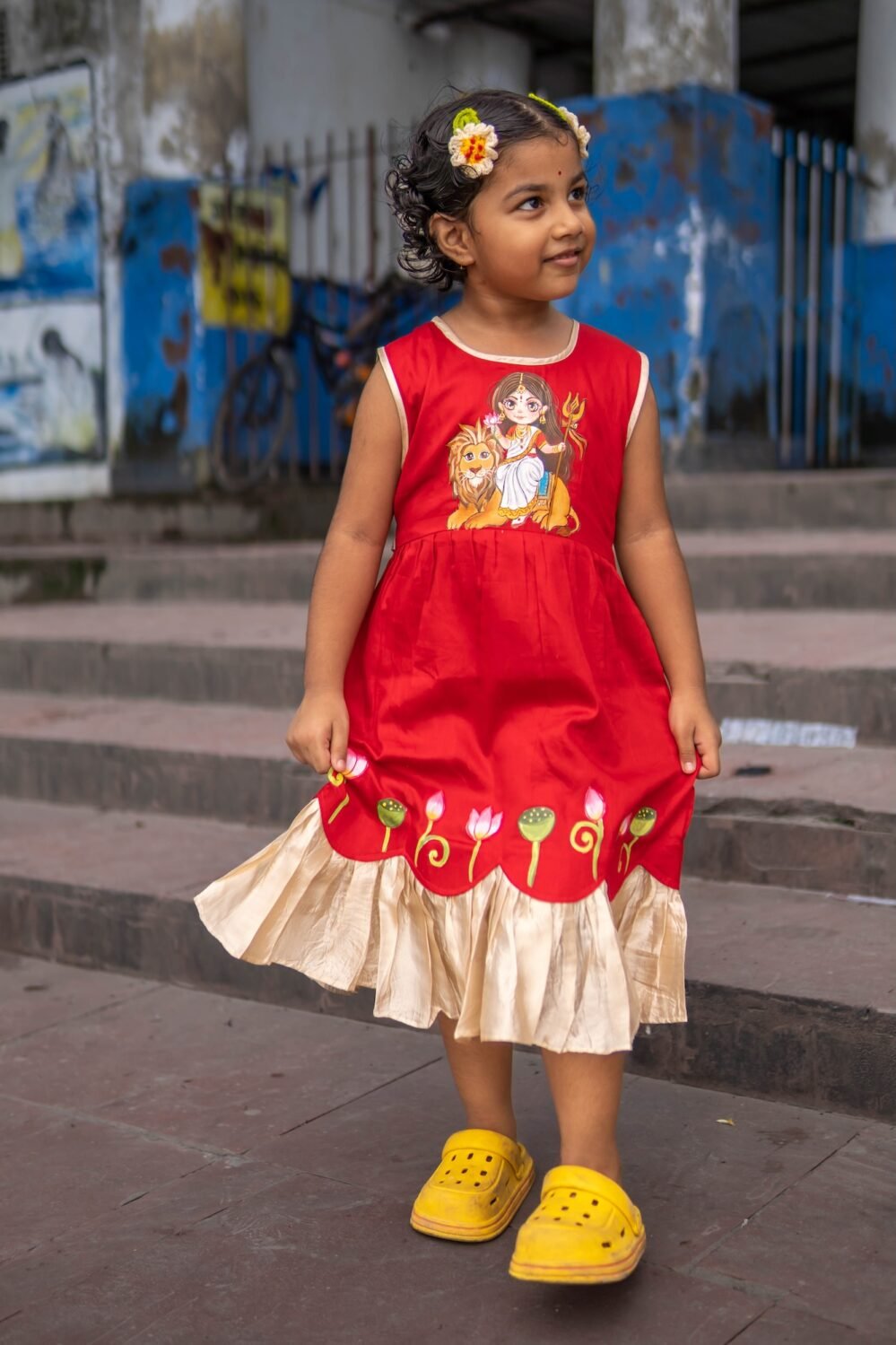 Smiling girl swaying in red malai cotton ethnic frock with golden frill hemline.