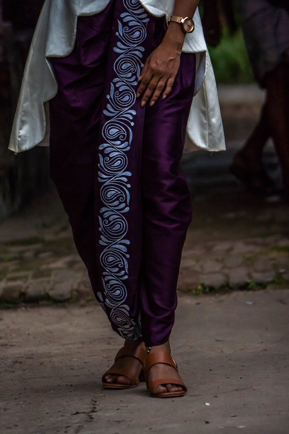 Close-up of white hand painted kalka paisley motif along the draped purple dhoti pants.