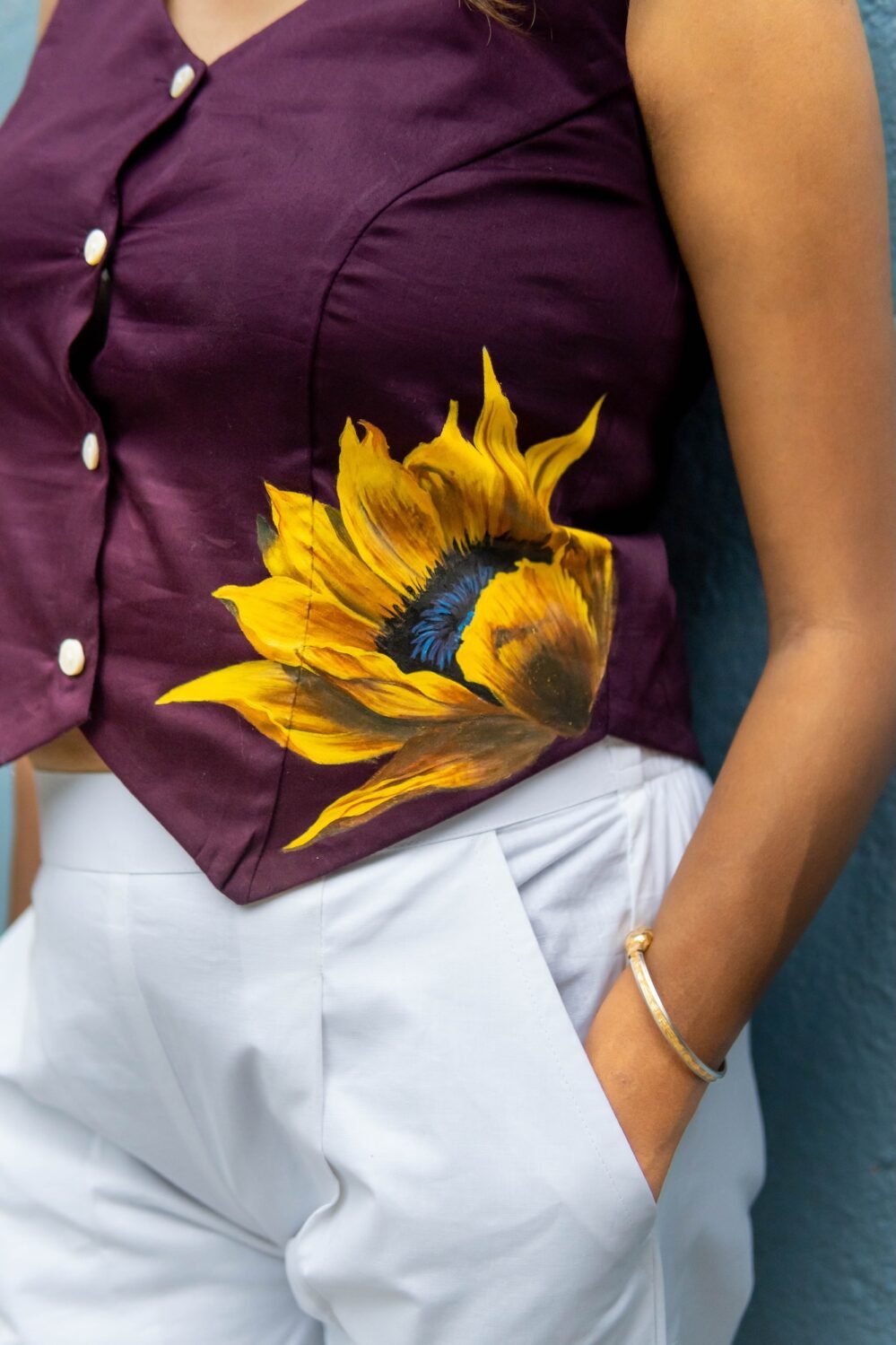 Close-up detail of the handpainted yellow sunflower motif on a purple Malai cotton waist coat hem.