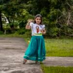 Young girl giving a peace sign in hand-painted Kanya Durga skirt set, perfect for festive celebrations.